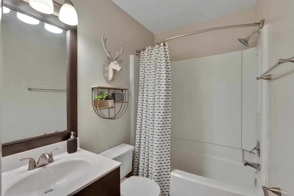 A white bathroom with dark cabinetry and a mirror with a dark brown frame