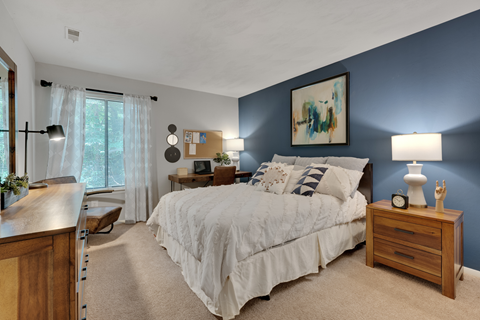 A bedroom with a large bed and a painting on the wall.