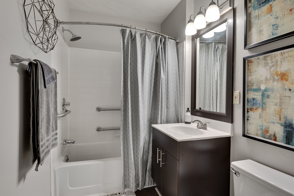 A bathroom with a white sink and a shower with a grey curtain.