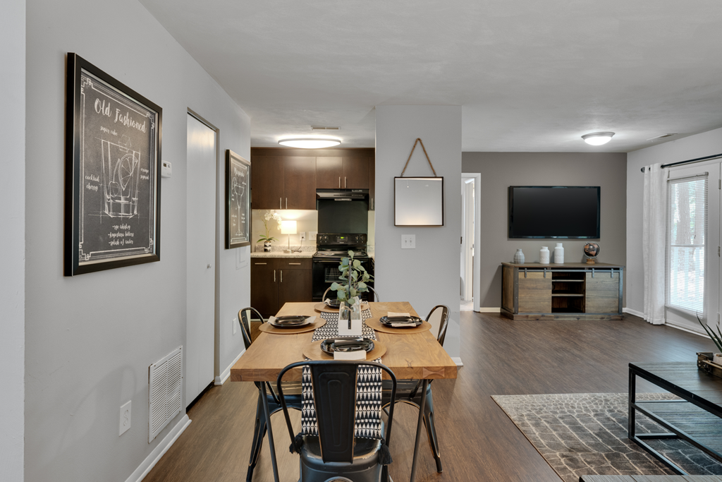 A dining room with a hardwood-style flooring, a wooden table and chairs.