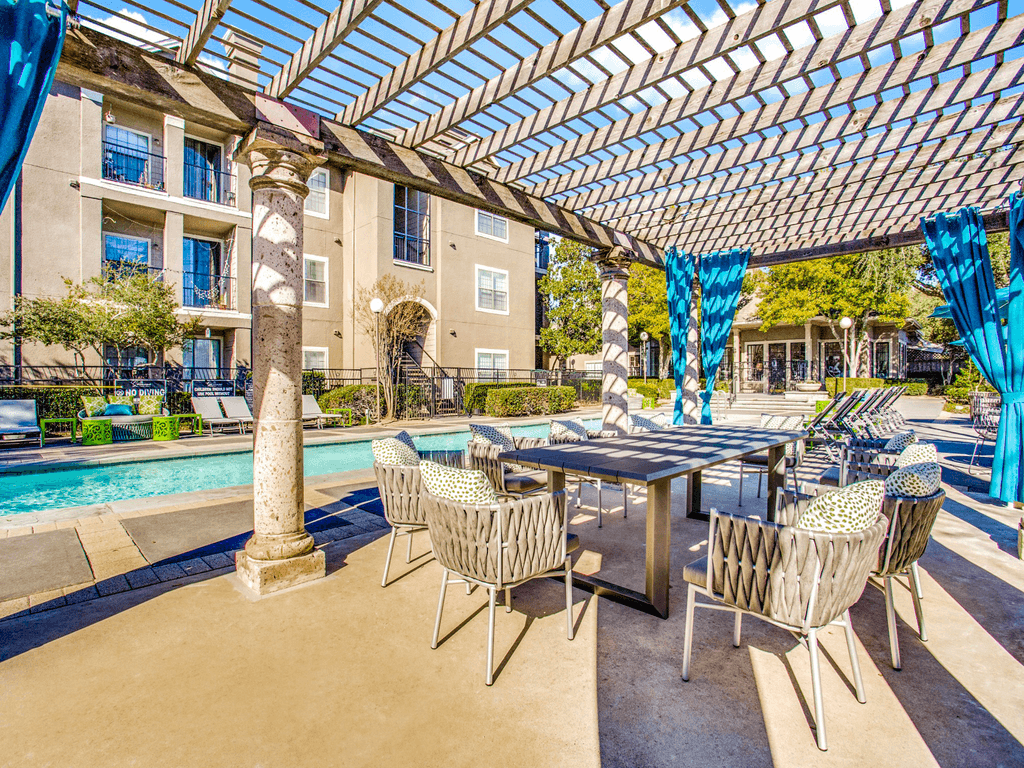 a patio with tables and chairs next to a swimming pool