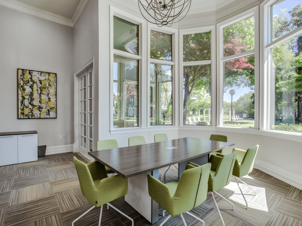 a conference room with a large window and a table with green chairs