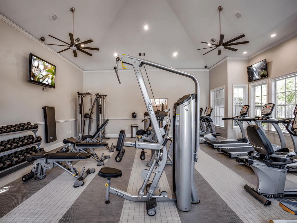 a gym with treadmills and other exercise equipment and a tv