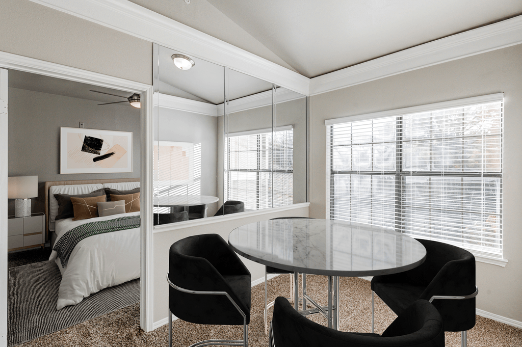 a bedroom with a bed and a glass table and chairs