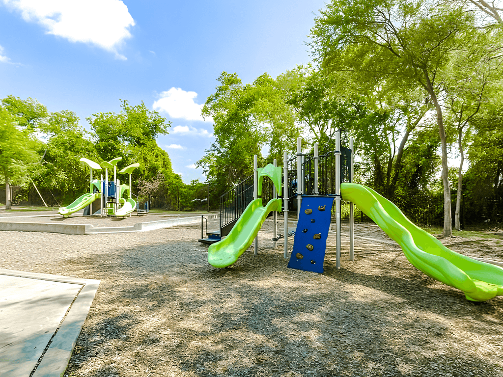 a playground with slides and trees in a park