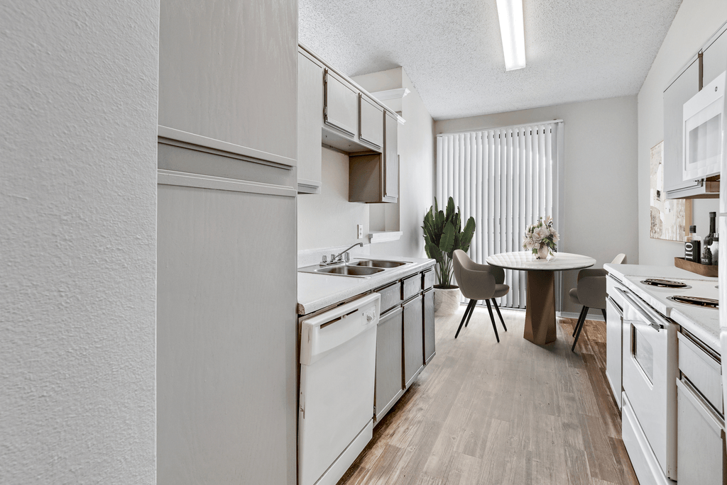 an open kitchen with white appliances and a dining room with a table