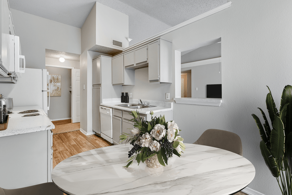 a kitchen and dining room with white cabinets and a table with flowers