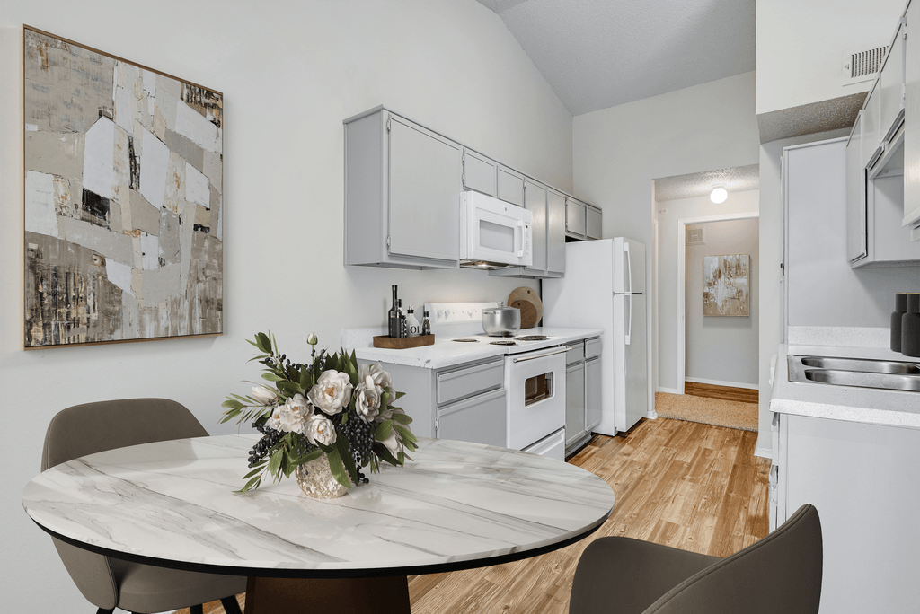 a kitchen with white appliances and a table with flowers