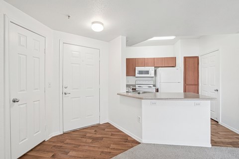 A kitchen with white cabinets and a wooden floor.