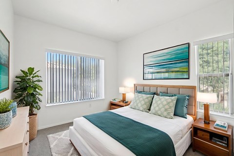 Bedroom with teal bedding and wood nightstands at Lake Pleasant Village Apartments, Peoria