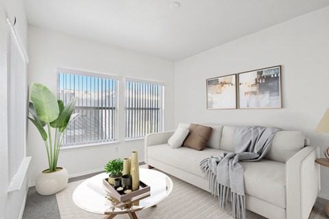 A living room with a white couch and a potted plant.