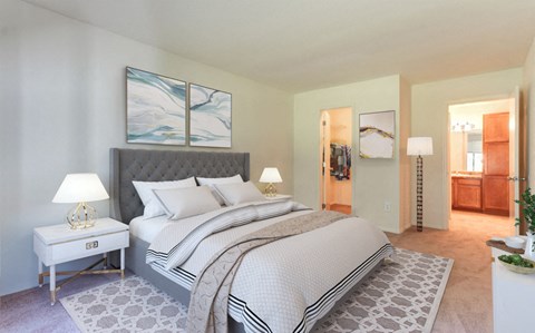 A bedroom with a large bed and a nightstand with a lamp.