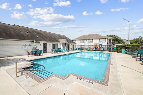 A large outdoor swimming pool with a slide and lounging chairs.