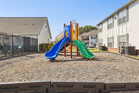 A playground with a blue slide and a green slide.