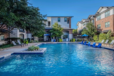 A swimming pool surrounded by lounge chairs and trees.