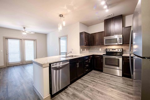A modern kitchen with dark brown cabinets and stainless steel appliances.