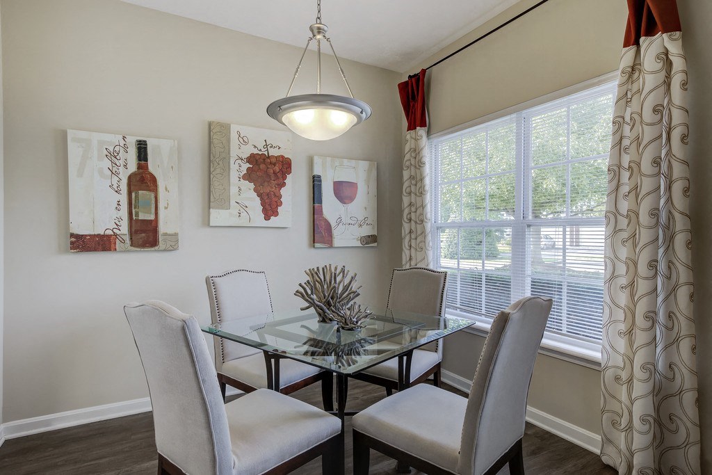 a dining room with a glass table and chairs and a window