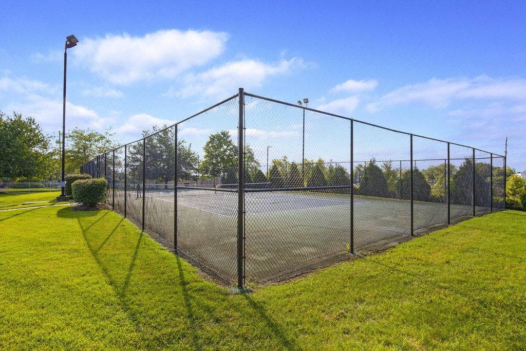 a fenced in tennis court with a net on the grass