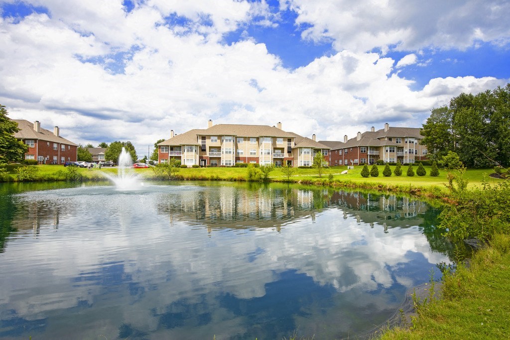 a pond with a fountain in front of a building