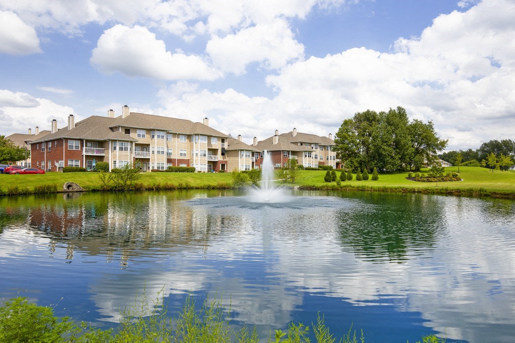 a fountain in the middle of a lake with buildings in the background