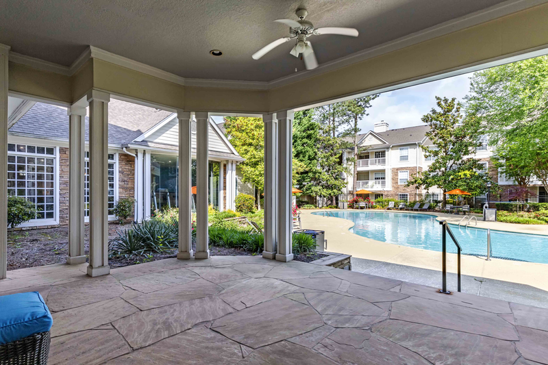 a covered patio overlooking a swimming pool with a ceiling fan
