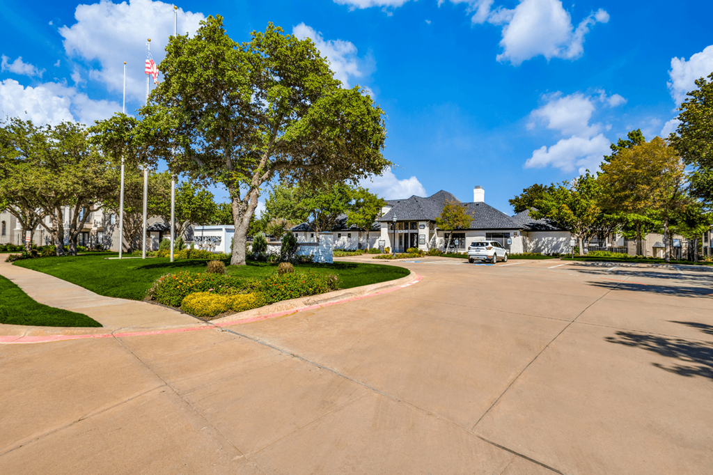an empty street in front of a house with trees and a driveway