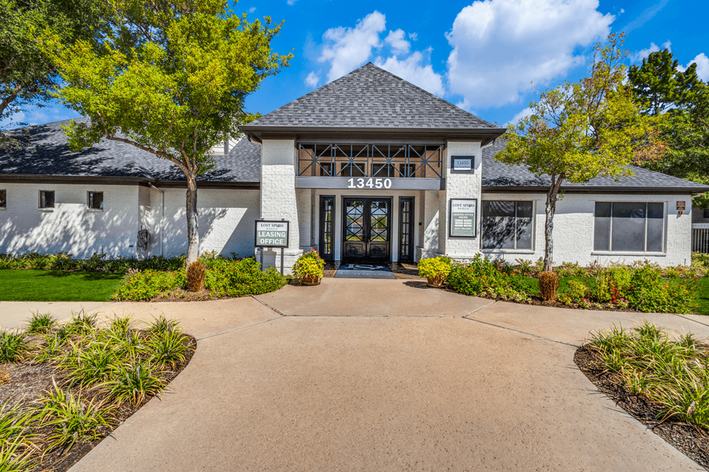the front entrance of a building with a driveway and trees