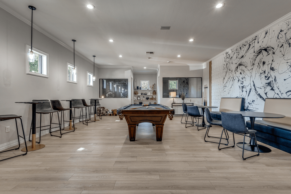 a community room with a pool table and tables and chairs