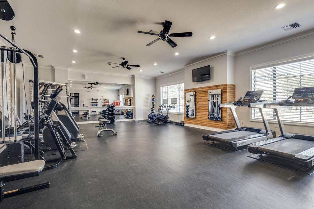 a gym with weights and cardio equipment and a window