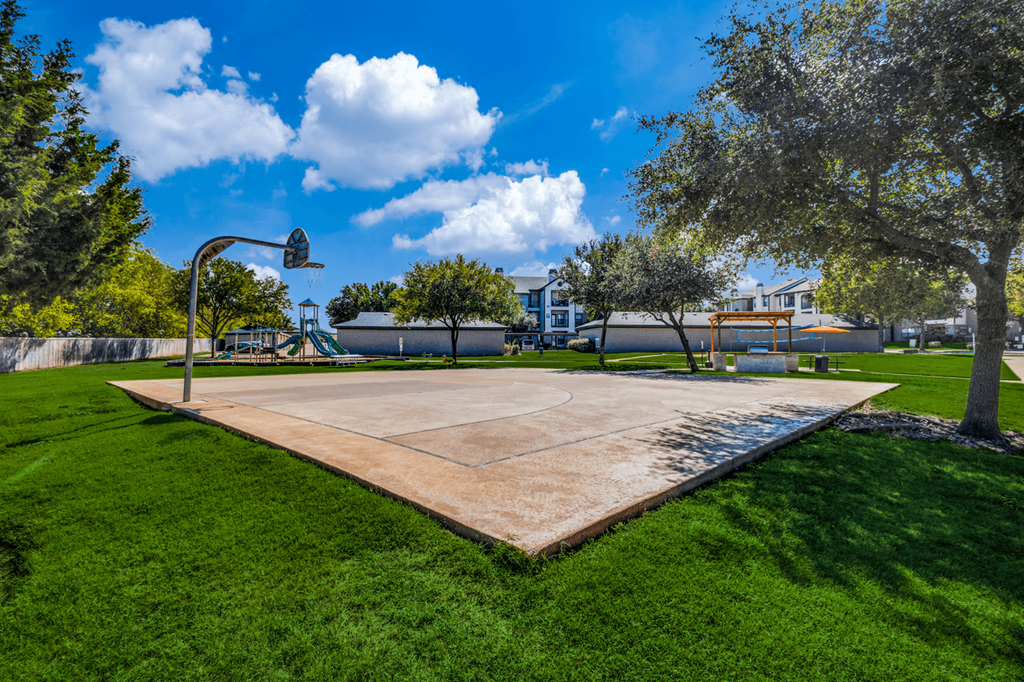 the basketball court is surrounded by green grass and trees