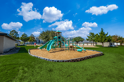 A playground with a green slide and a sandbox.