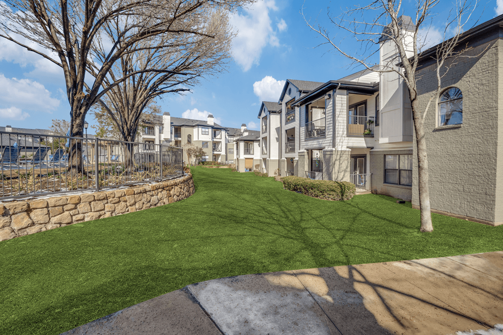 our apartments have a spacious yard with green grass and a stone wall