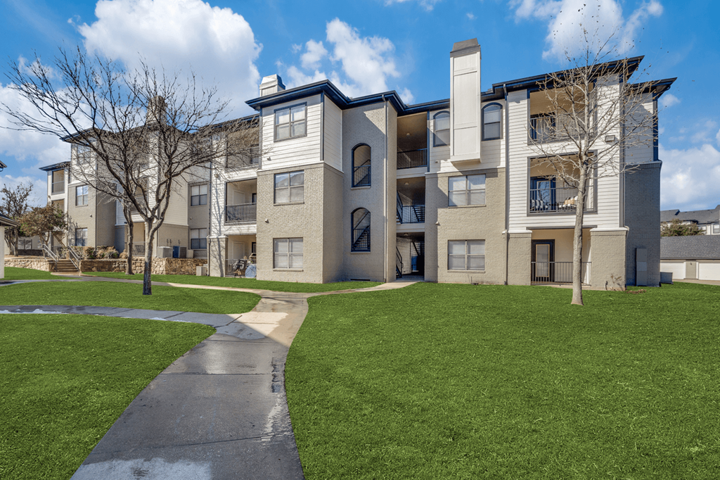 an exterior view of an apartment building with green grass and sidewalks
