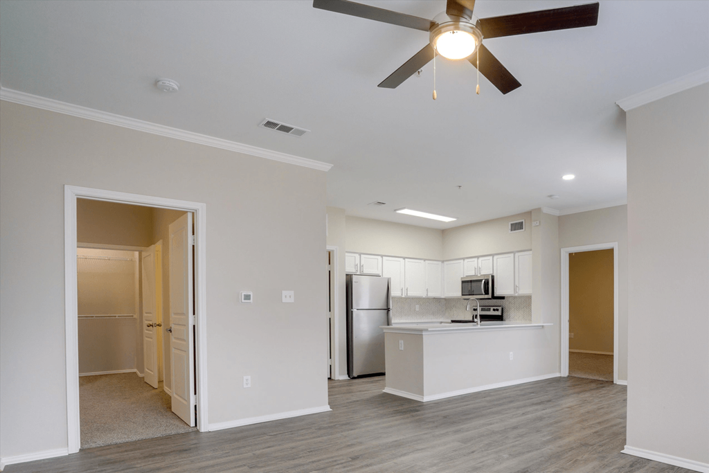 an empty living room and kitchen with a ceiling fan