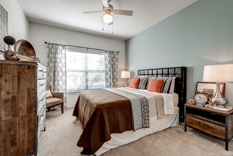 A bedroom with a bed, nightstand, and a ceiling fan.