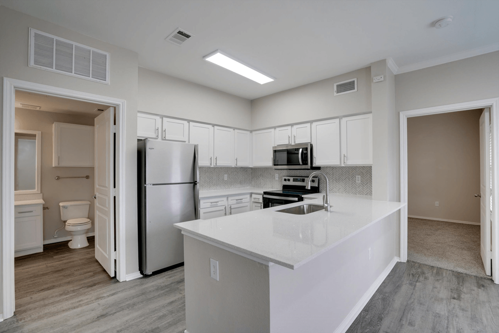a white kitchen with stainless steel appliances and a white counter top