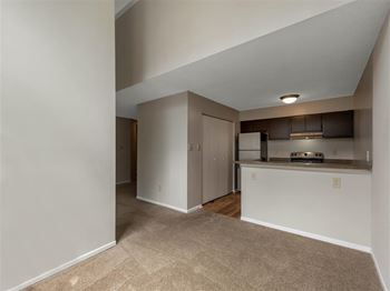 View of Kitchen with Brown Cabinets and Stainless Steel Appliances From Carpeted Living Room