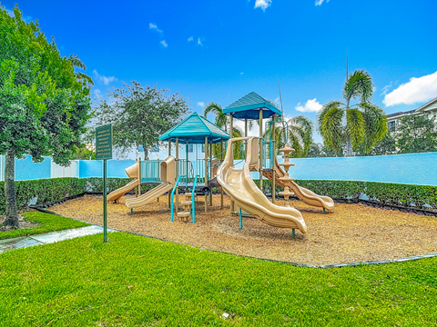 A playground with a blue and yellow slide and a green roofed structure.