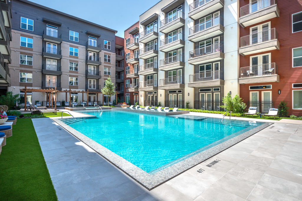 Swimming pool with lounge chairs, tanning shelf, pergolas and building exterior surrounding
