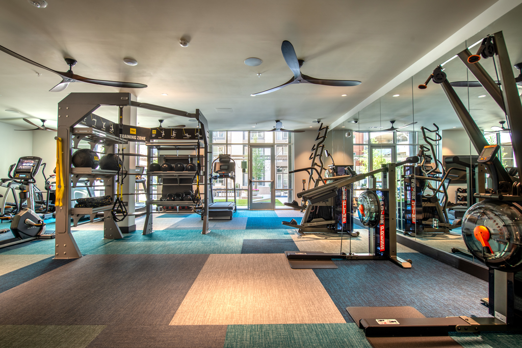 Fitness center with cardio and strength machines, ceiling fans and large mirror wall