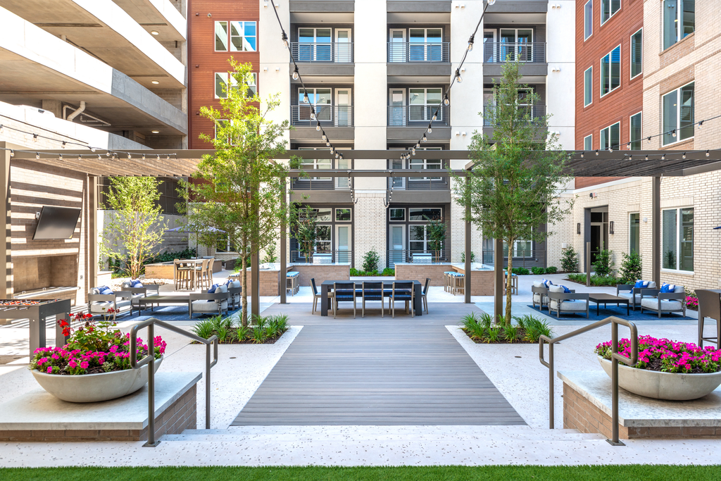 Courtyard outdoor gaming area with foosball table, alfresco seating with gas grill area and pergolas and wall mounted television