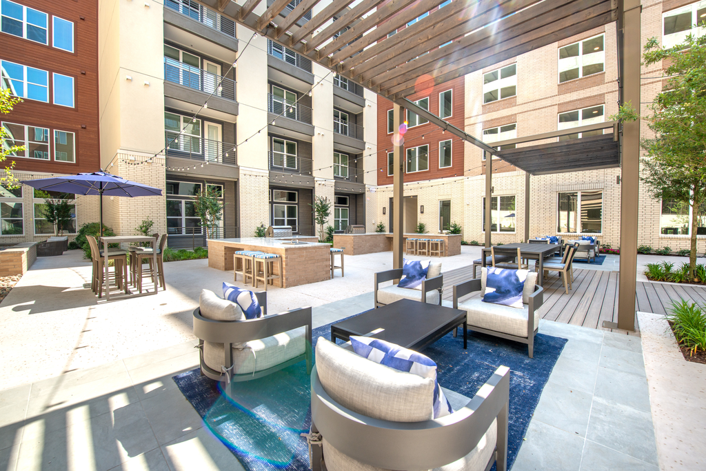 Courtyard lounge with seating area with pergolas, high top table with umbrellas, grills