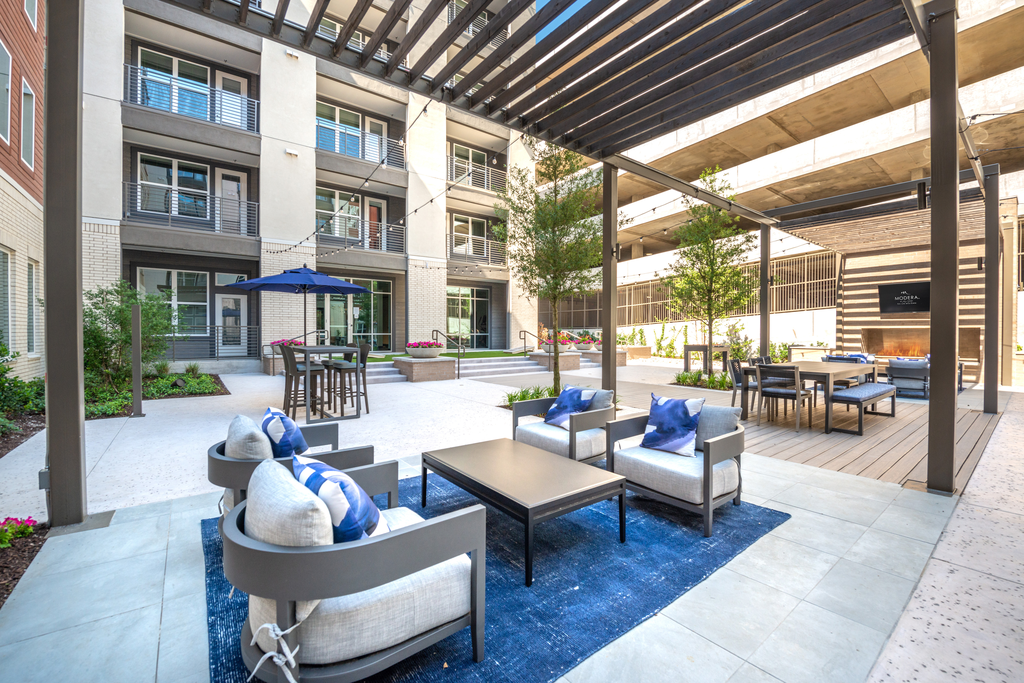Courtyard lounge with seating area with pergolas, high top table with umbrellas, wall mounted television and gas fireplace