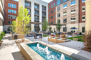 Fountain water feature near courtyard lounge and outdoor gaming area with foosball tables, cornhole and native landscape - Photo Gallery 12