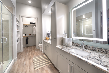 Staged bathroom with granite countertops, dual vanities, custom lighted vanity mirrors, wood style flooring, built-in shelving and direct access to walk in closet - Photo Gallery 46