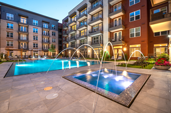 Zero edge swimming pool with heated spa, fountains, lounge chairs, tanning shelf and pergolas with building exterior surrounding - Photo Gallery 3