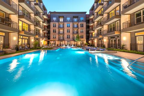 Zero edge swimming pool with tanning shelf, lounge chairs, pergolas and building exterior surrounding