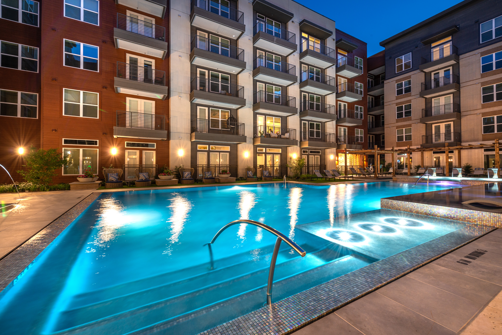 Zero edge swimming pool with tanning shelf, lounge chairs, pergolas and building exterior surrounding
