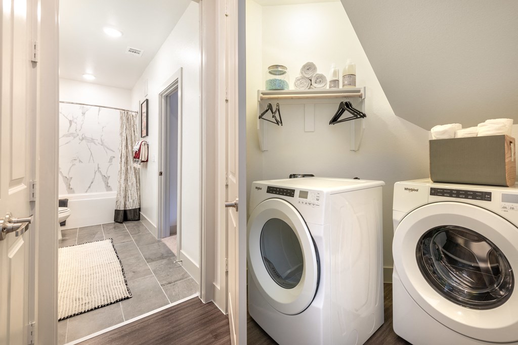 Inside of walk-in closet facing in-unit washer and dryer facing into the bathroom