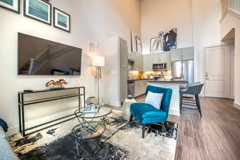 Living room area facing the kitchen and a television next to a blue velvet chair. - Photo Gallery 83
